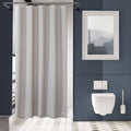 Light grey shower curtain hanging in a bathroom over a shower stall opening