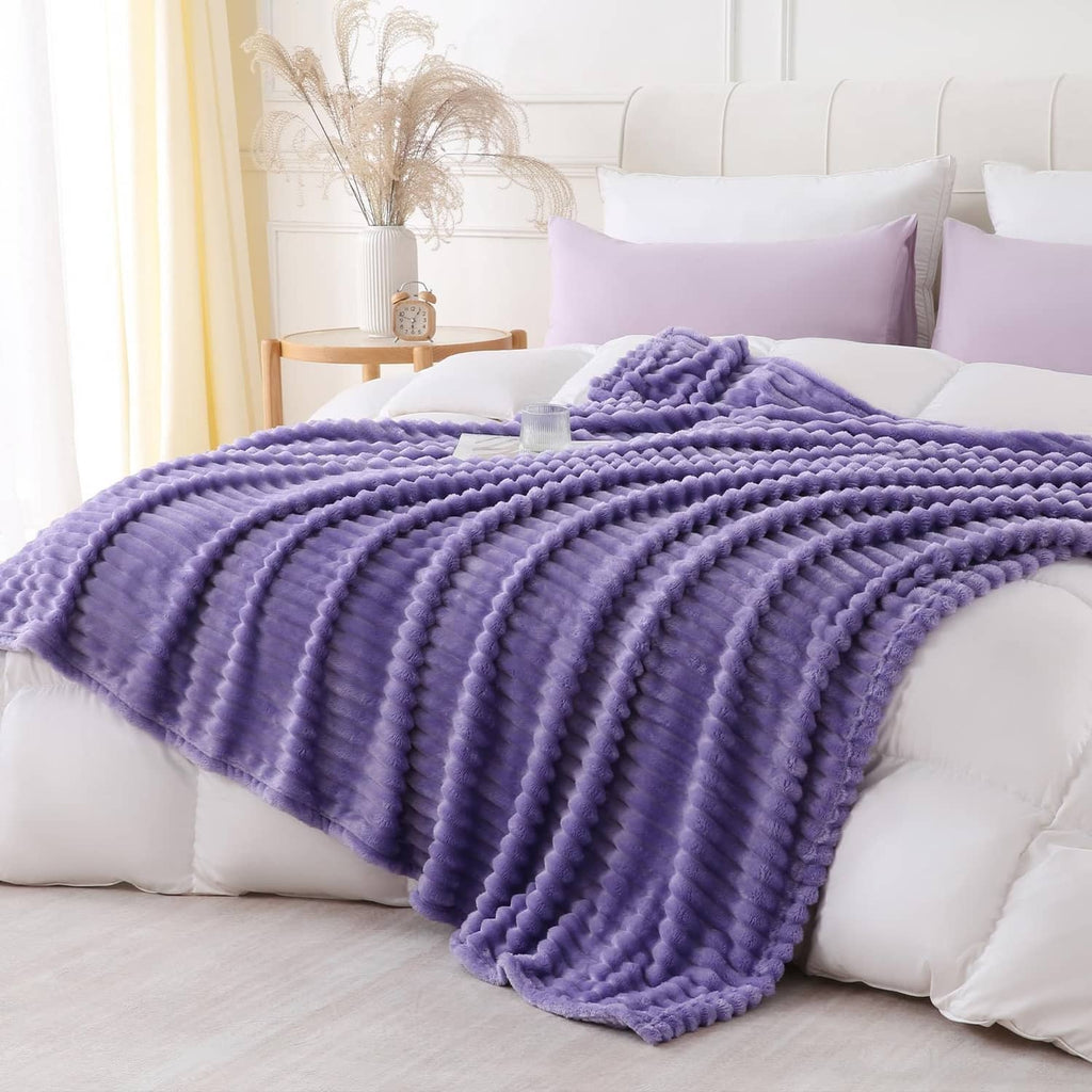 Lavender plush throw blanket with ribbed loop pattern, laid over bed