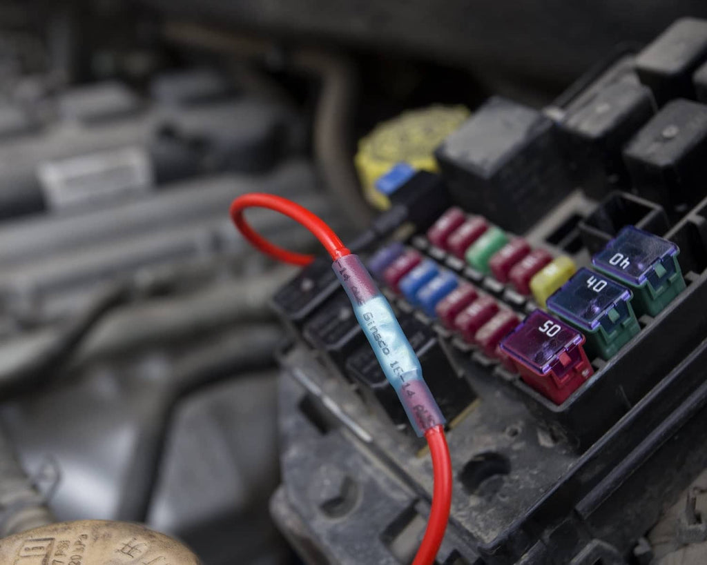 Automotive wiring with heat-shrink crimp connectors on red and blue wires near fuse blocks