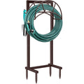 Bronze garden hose holder with teal coiled hose loop and four pointed ground spikes