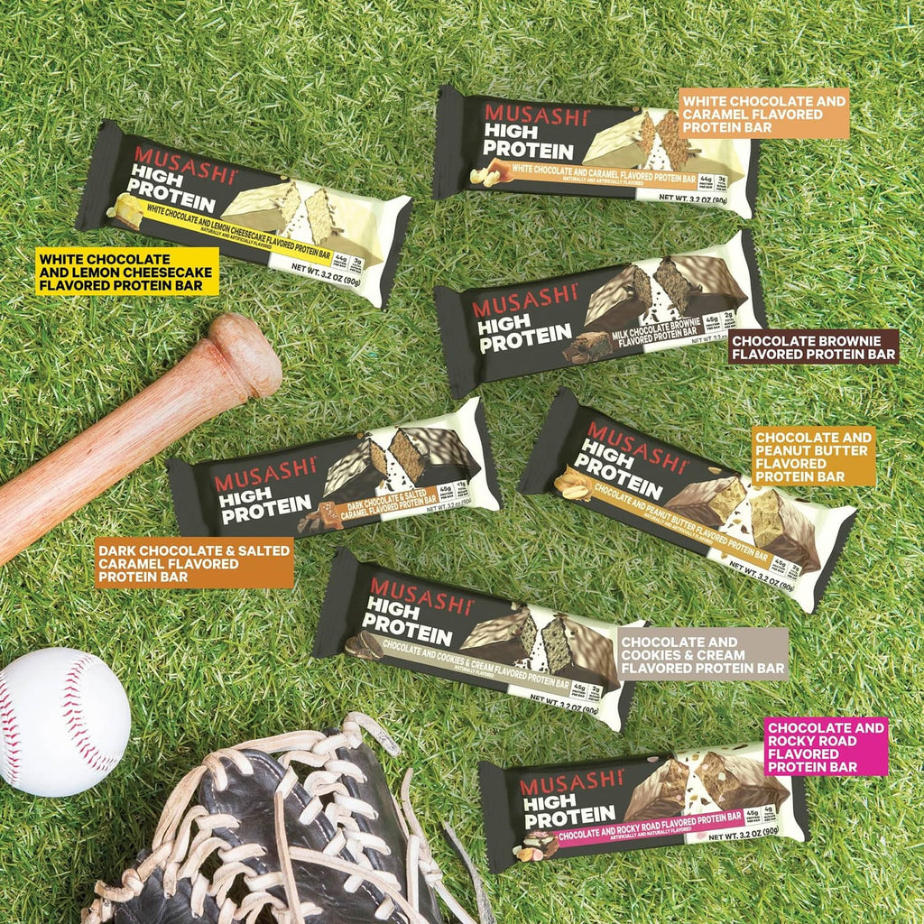 Assorted protein bars on grass, including white chocolate and lemon cheesecake bar
