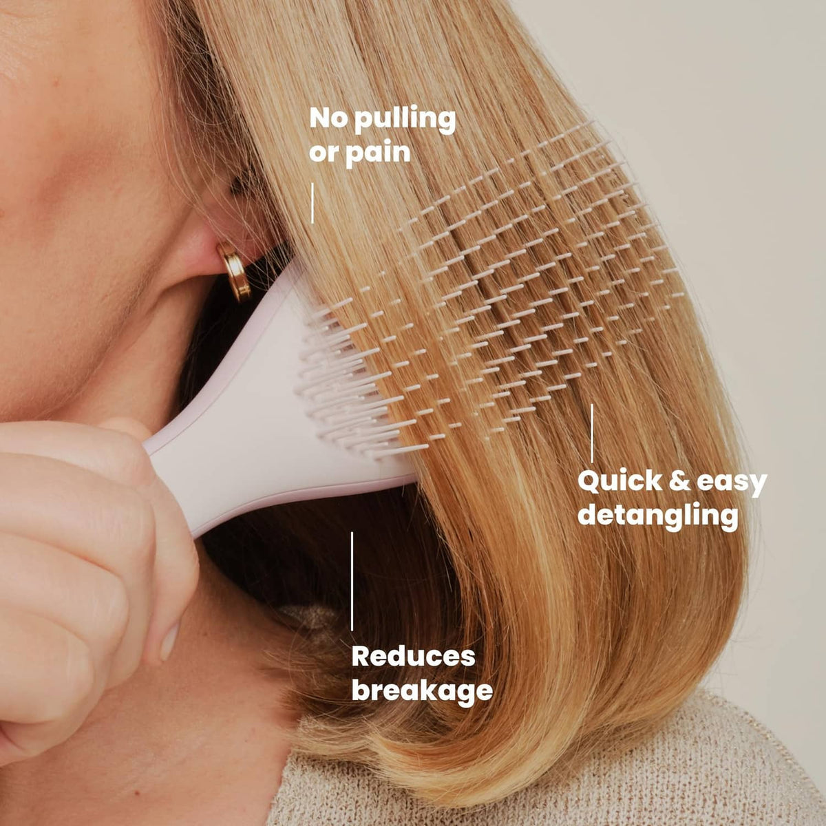 Pink Frost detangling hairbrush brushing through blonde hair near the ear