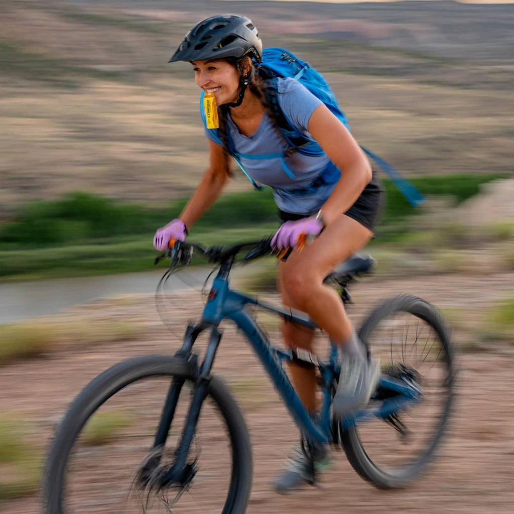 Cyclist holding a Honey Stinger Gold energy gel packet during an outdoor ride