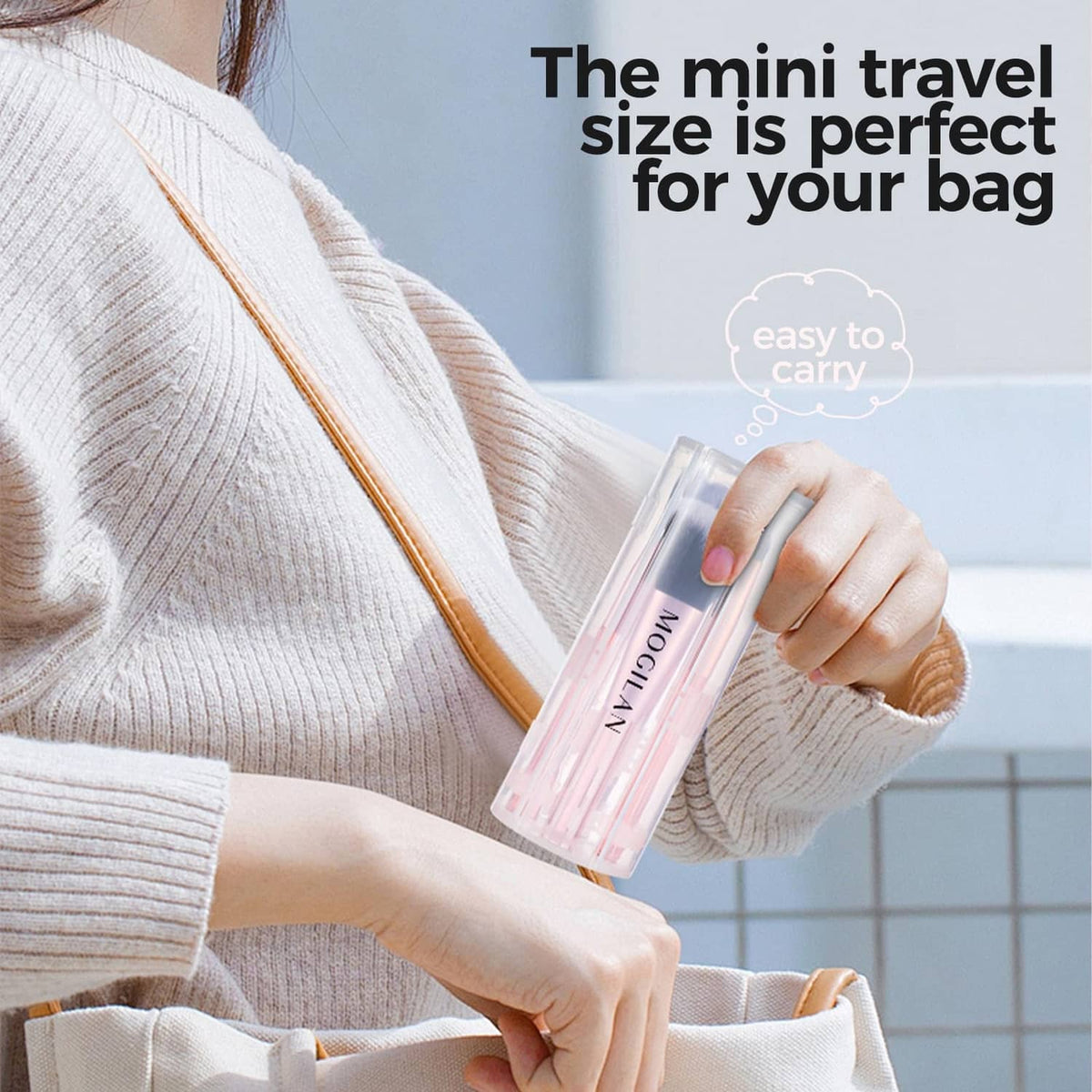 Mini travel makeup brush set in clear pink case held in hand for easy bag carry