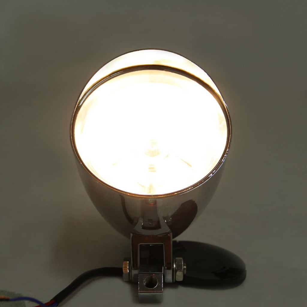 Motorcycle bullet headlight front view with bright illuminated lens in chrome housing