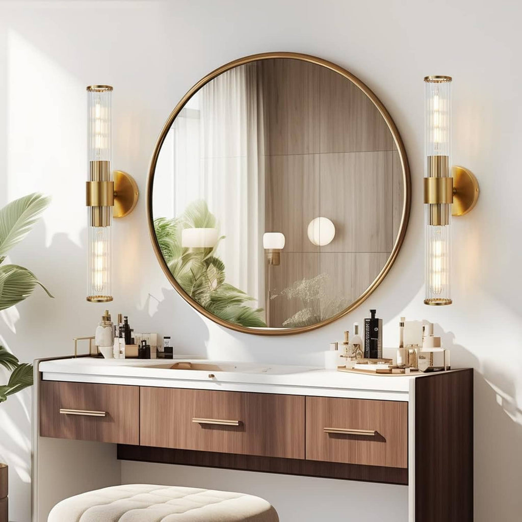 Gold vanity light 2-pack with clear glass tube shades and round backplates on wall.