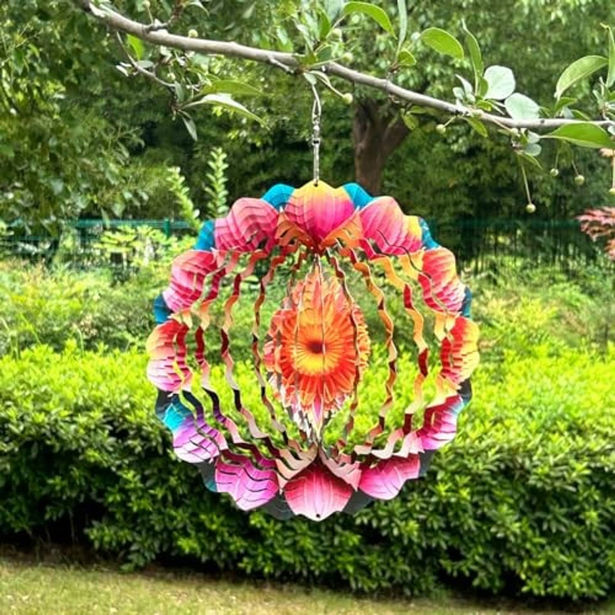Colorful metal mandala wind spinner with layered petals, hanging from a tree branch