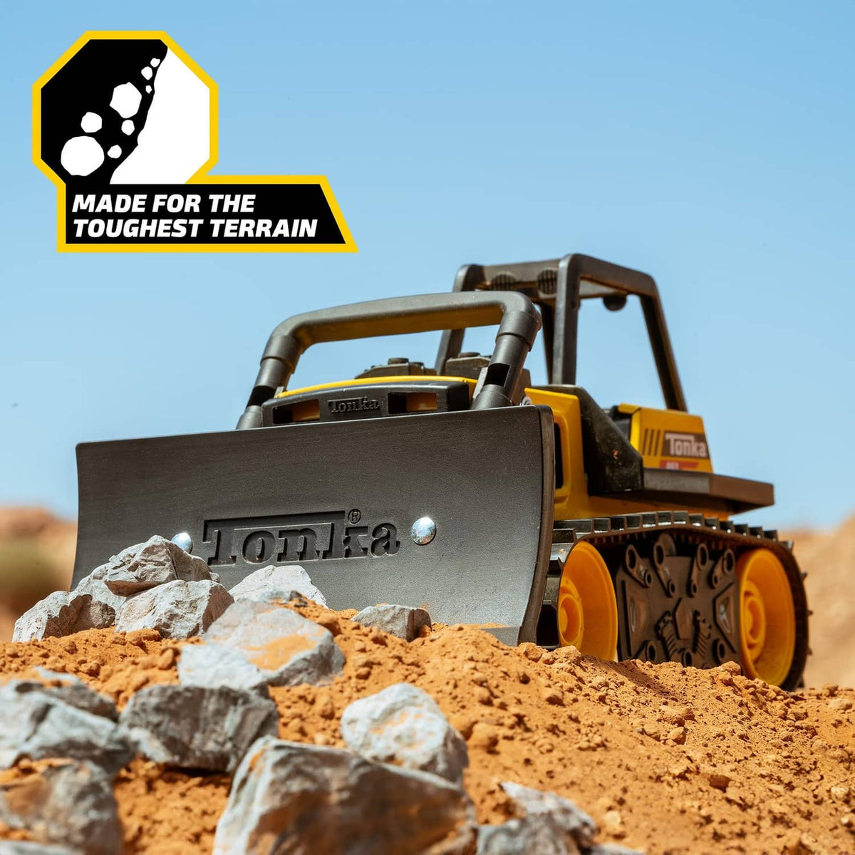 Yellow Tonka bulldozer toy with front blade in rocky terrain
