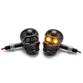 Black metal skull LED amber turn signal pair with chrome screw mounts and glowing eyes