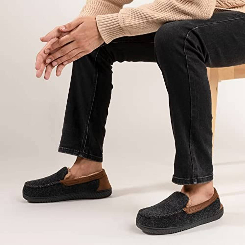 Men's moc slipper on foot, dark charcoal knit with brown strap and tan lining