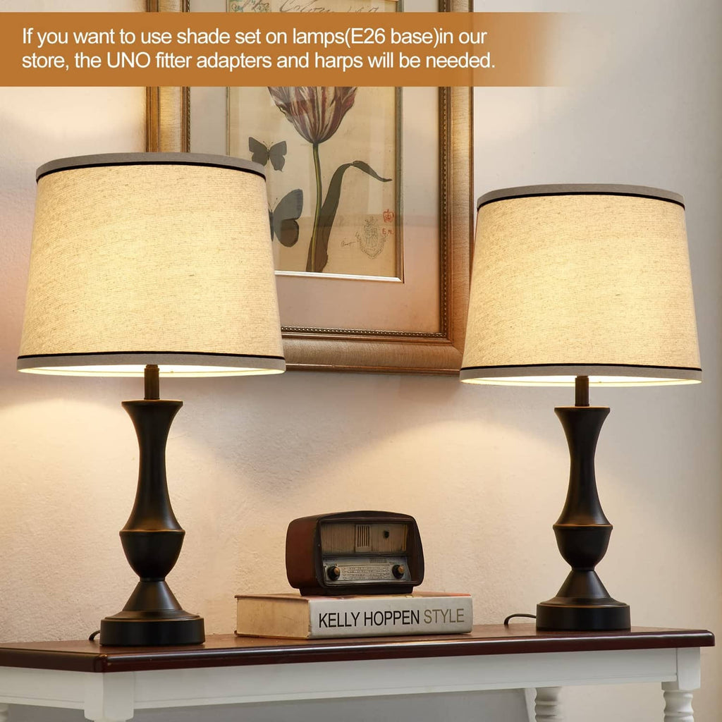 Pair of beige drum lamp shades with black trim on table lamps