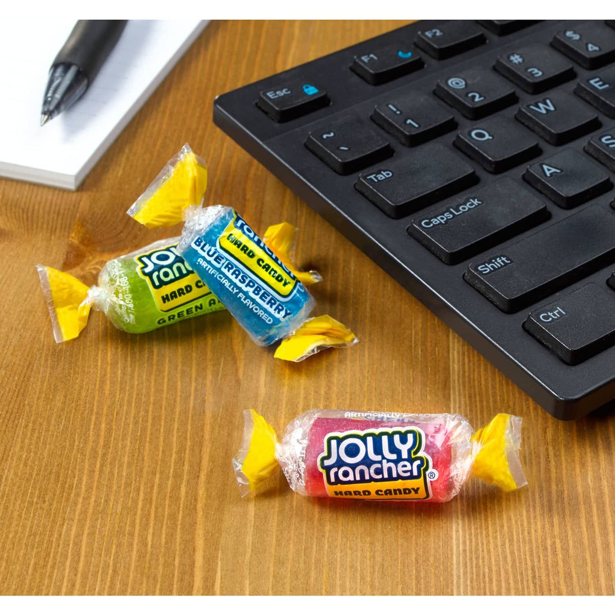 JOLLY RANCHER fruit hard candies in yellow wrappers on a wooden table