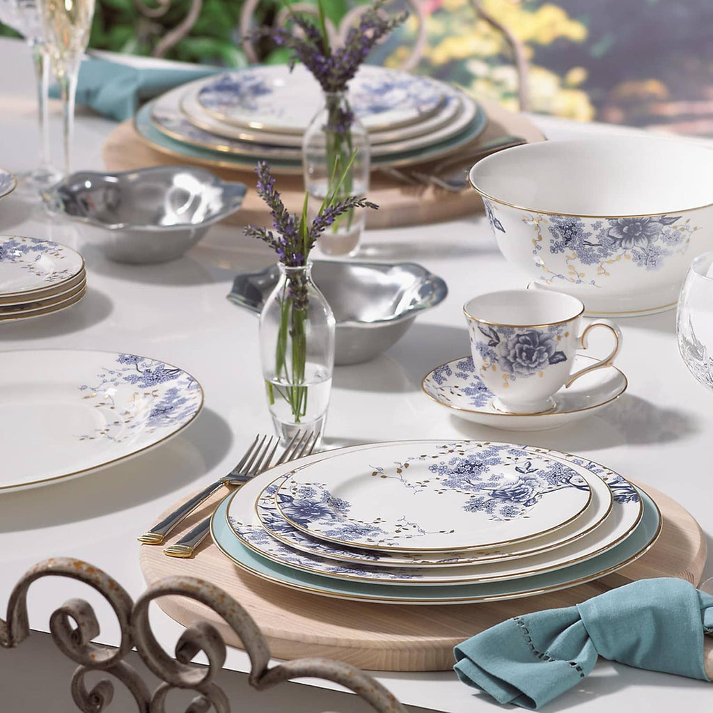 Assorted porcelain plates and teacups with blue floral pattern and gold trim on a table