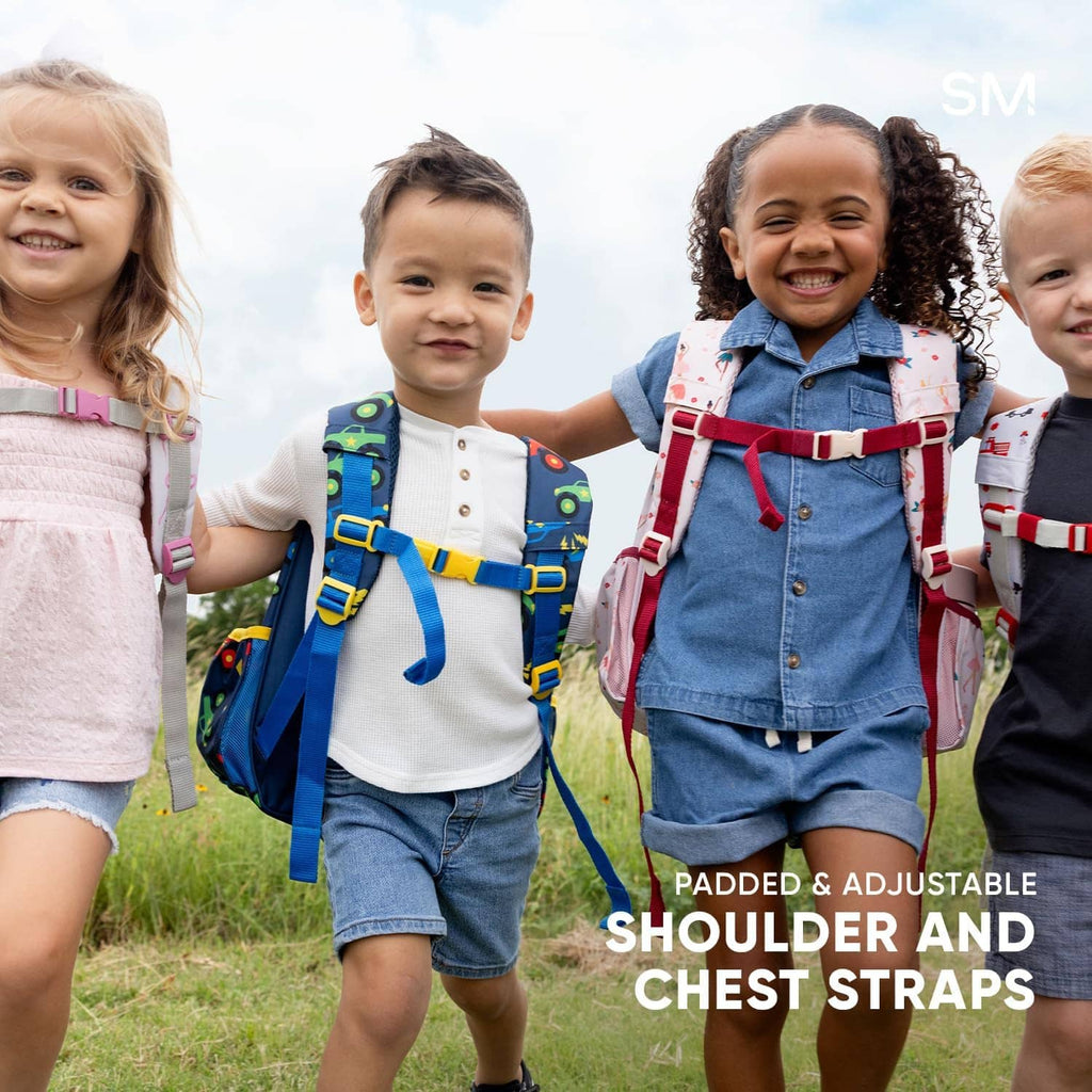 Kids wearing toddler backpacks with colorful vehicle-themed prints on grassy field