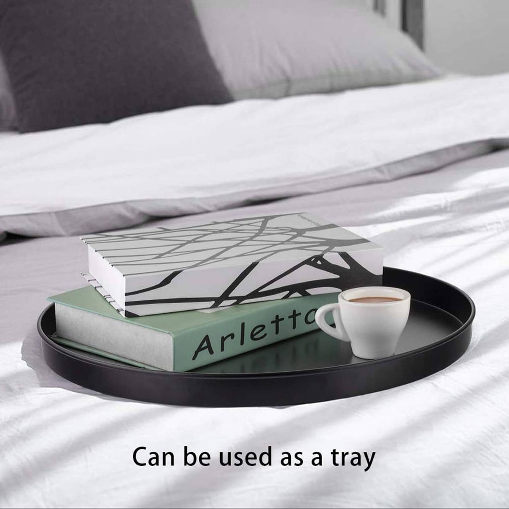 Black round metal tray-style side table with magazines and a cup on top
