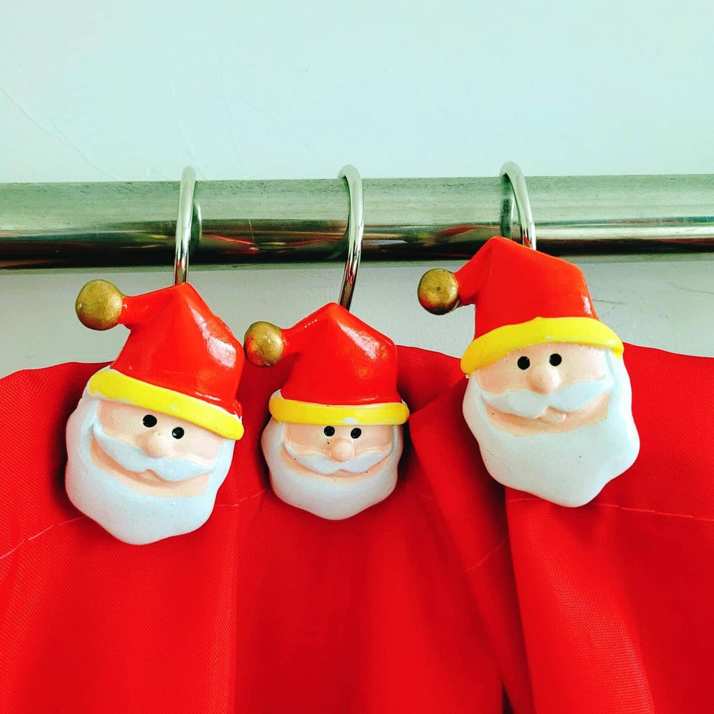 Red shower curtain with three small holiday-face ornaments clipped along top rings