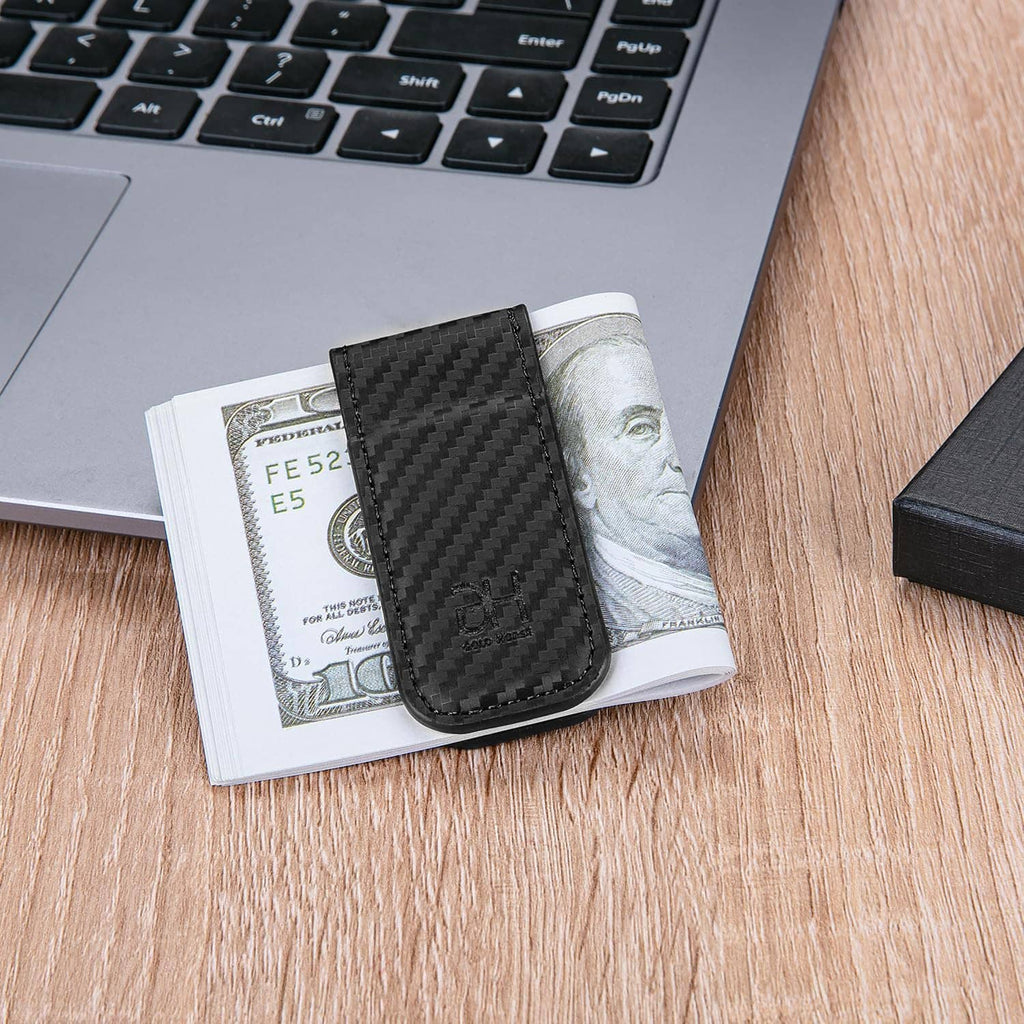 Black carbon-fiber money clip card holder on a table with folded bills nearby