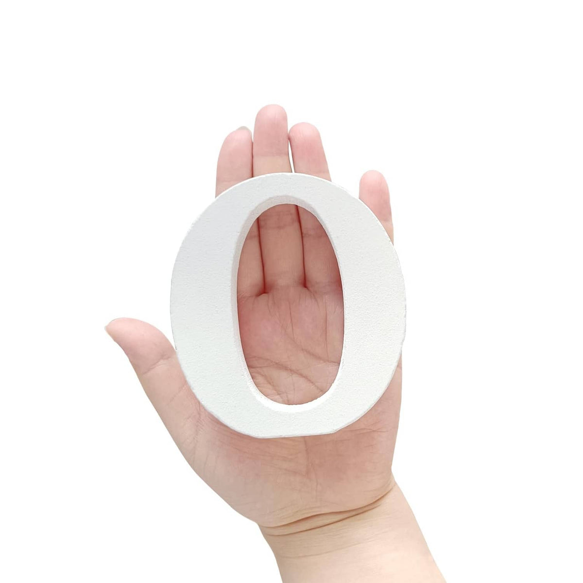 White unfinished wood marquee letter O held in hand, showing inner oval cutout