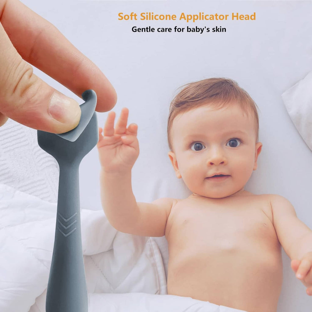 Dark blue silicone diaper cream spatula applicator with soft head, held near baby