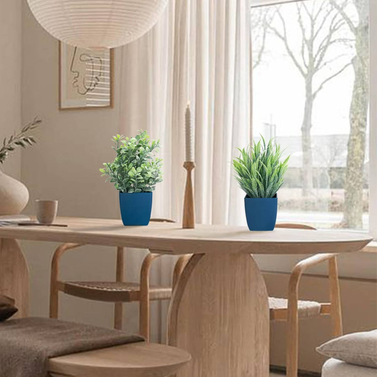 Two artificial plants in blue pots for home decor: leafy shrub and spiky eucalyptus