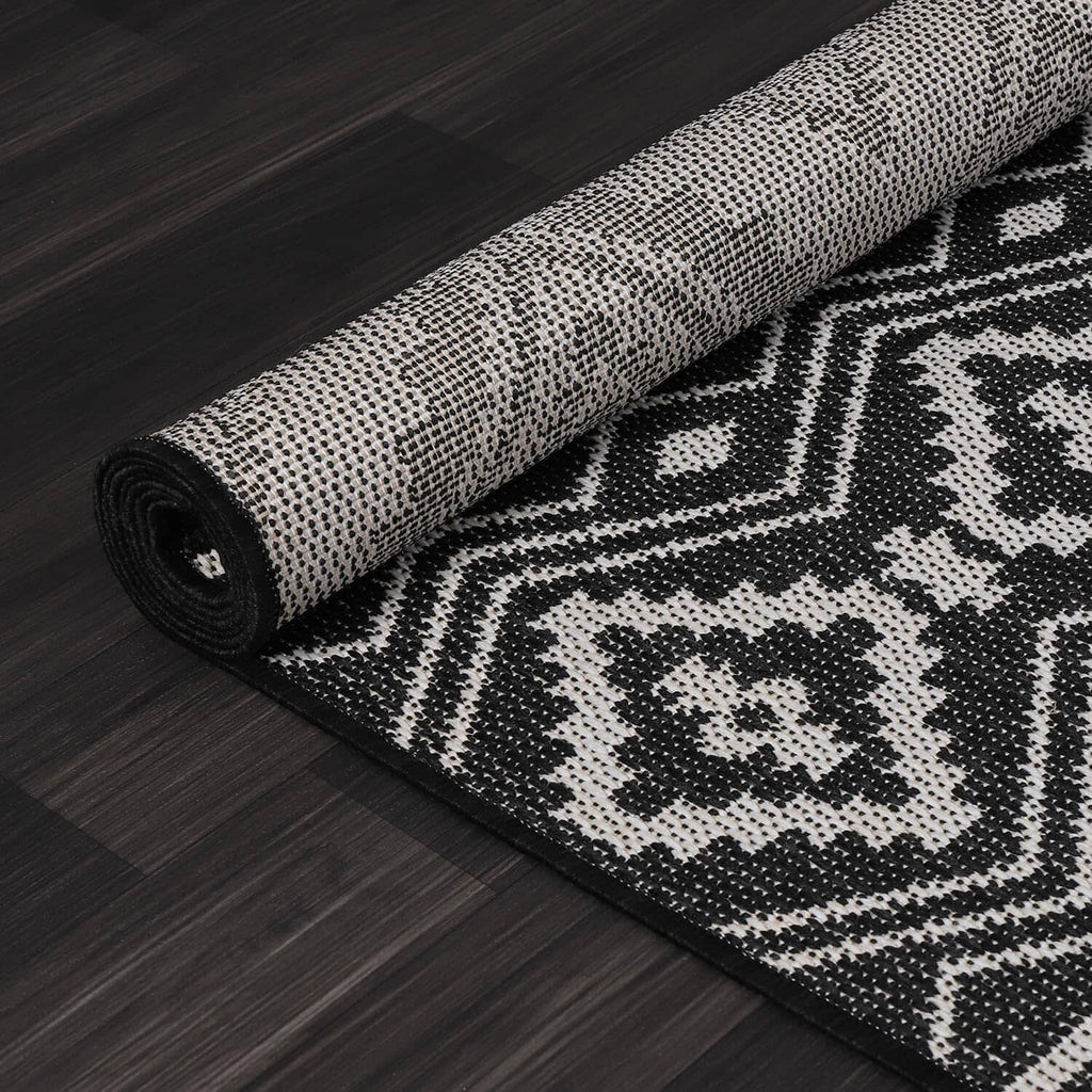 Close-up of rolled black-and-white rug with dense geometric weave texture