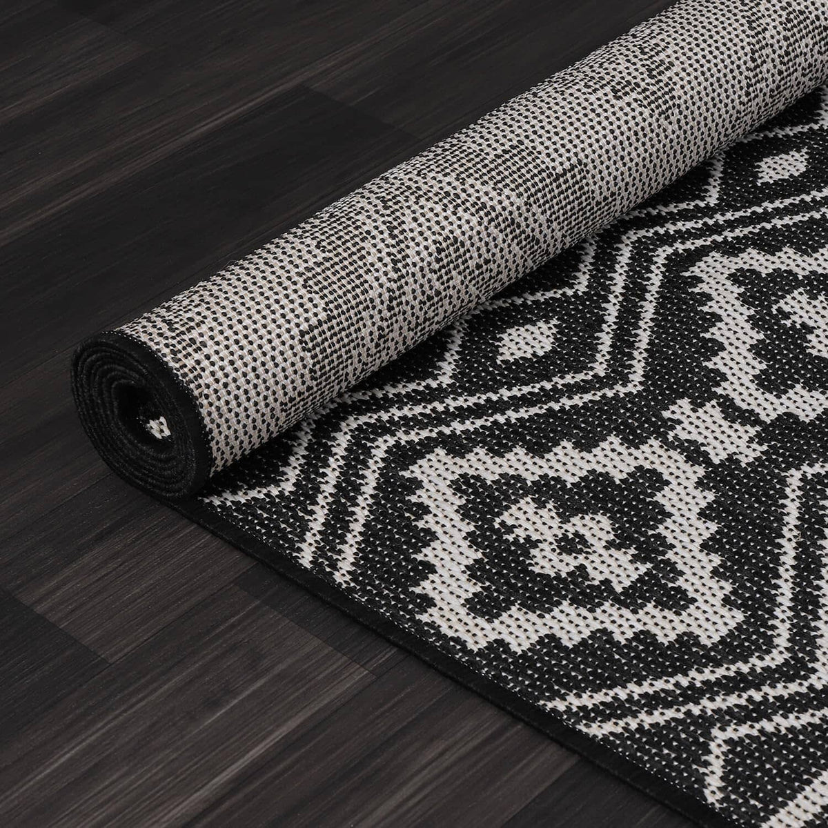 Close-up of rolled black-and-white rug with dense geometric weave texture