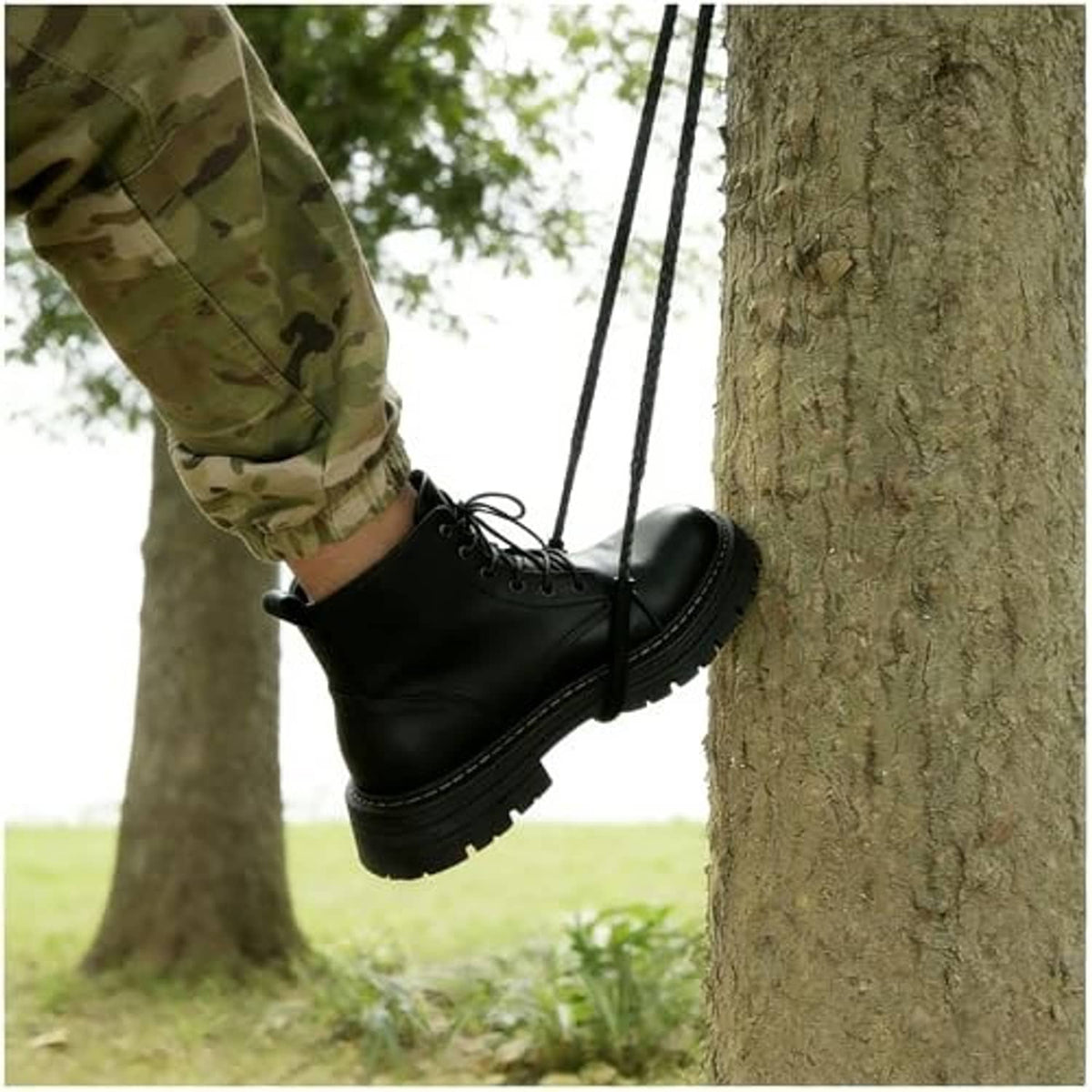 Black climbing strap ladder with foot hold loops, secured between tree trunks