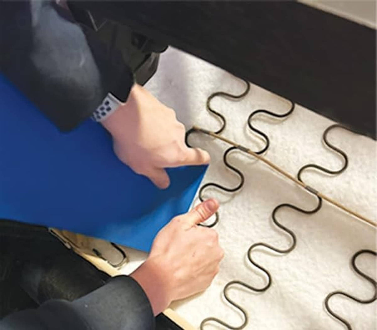 Hands placing blue support pad onto interlocking spring inserts