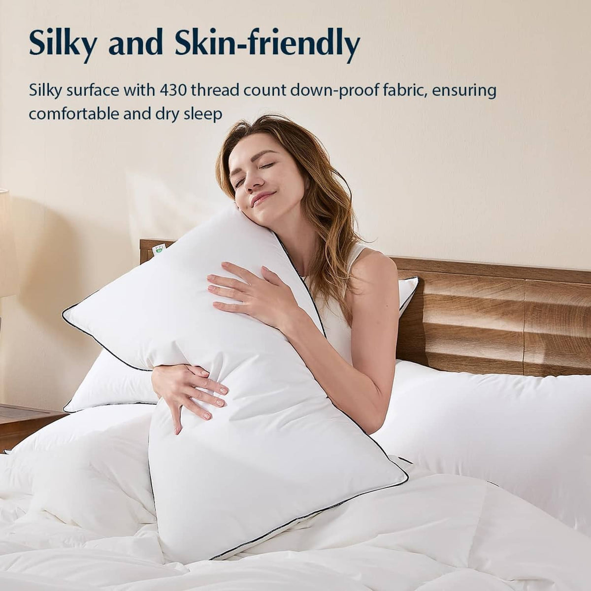 White down fiber pillow with dark piping, held by person for silky feel