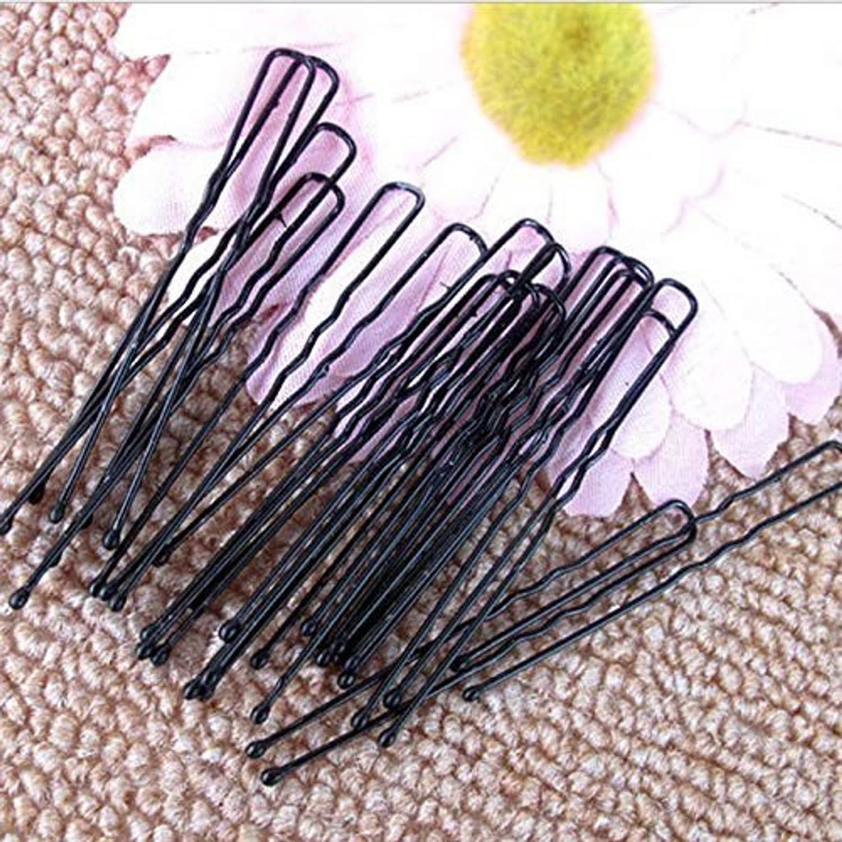 Black U-shaped bun hair pins laid out, multiple pins