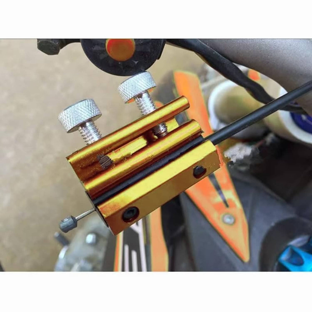 Gold cable lubrication tool clamped to cables with two knurled threaded knobs.