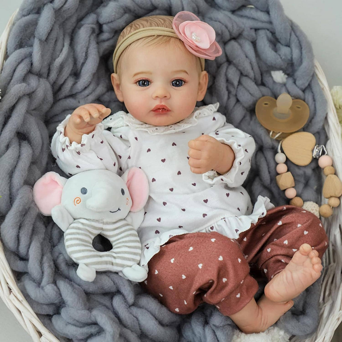 Realistic 18-inch reborn baby girl doll with plush mouse toy and brown patterned pants.