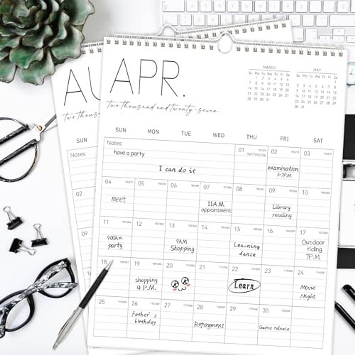White vertical wall calendar on desk with detailed monthly grid and notes section