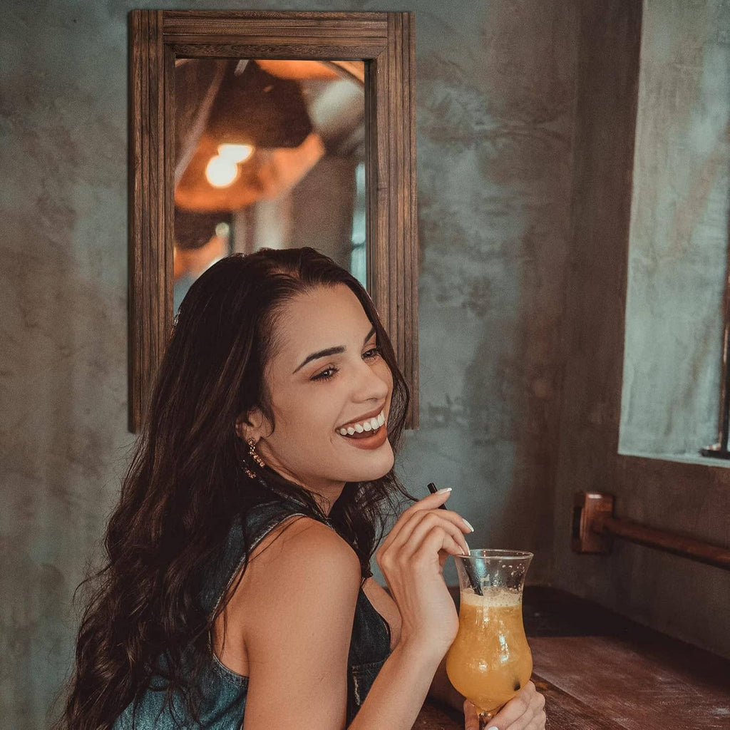 Rustic rectangular wooden wall mirror frame behind a smiling person.