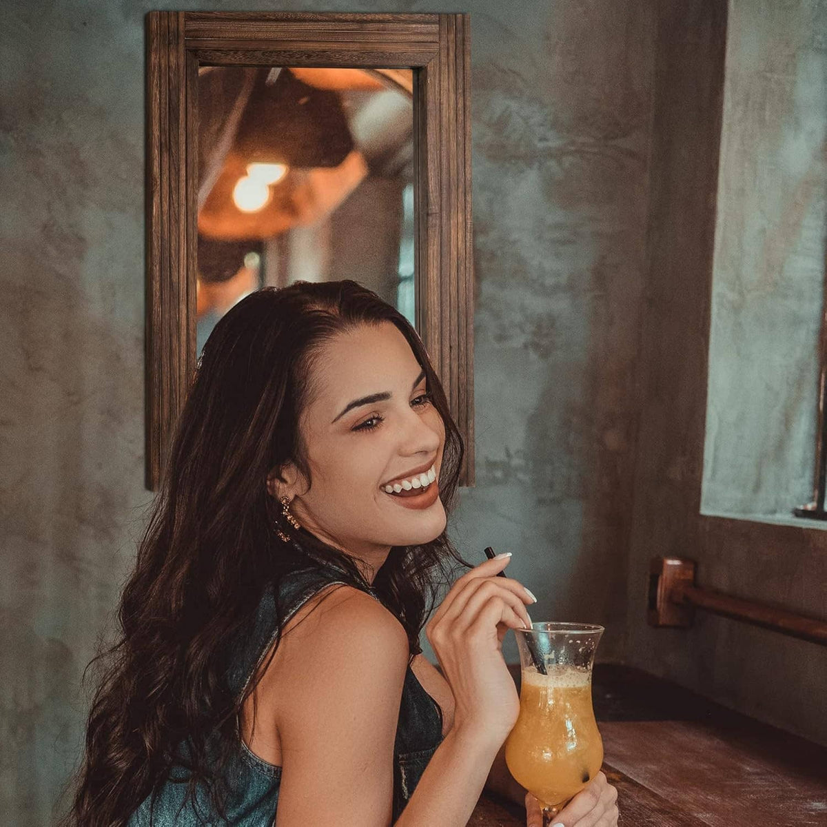 Rustic rectangular wooden wall mirror frame behind a smiling person.