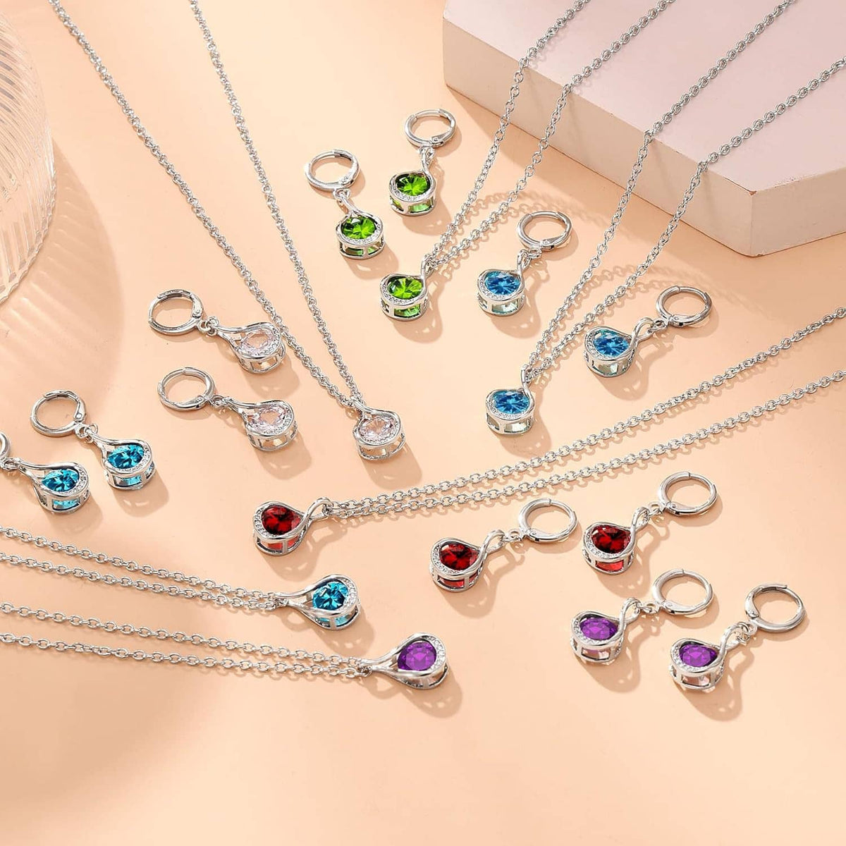 Assorted silver charm necklaces with colorful teardrop gemstones and matching hoop pendants