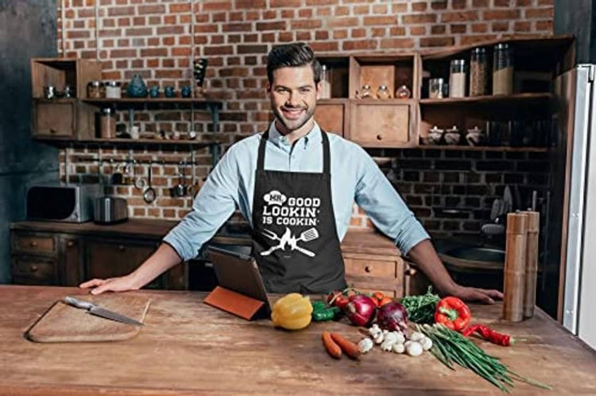 Black cotton apron with 'MR. GOOD LOOKIN' IS COOKIN' graphic worn at workbench