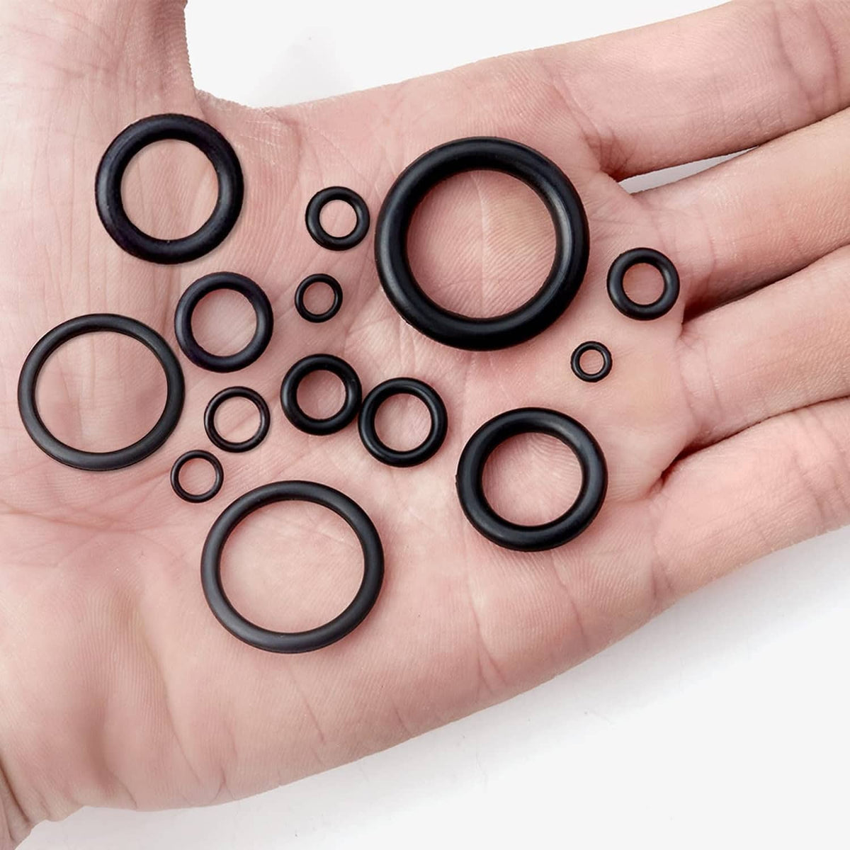 Assorted black O-rings held in hand, with several large and small rings