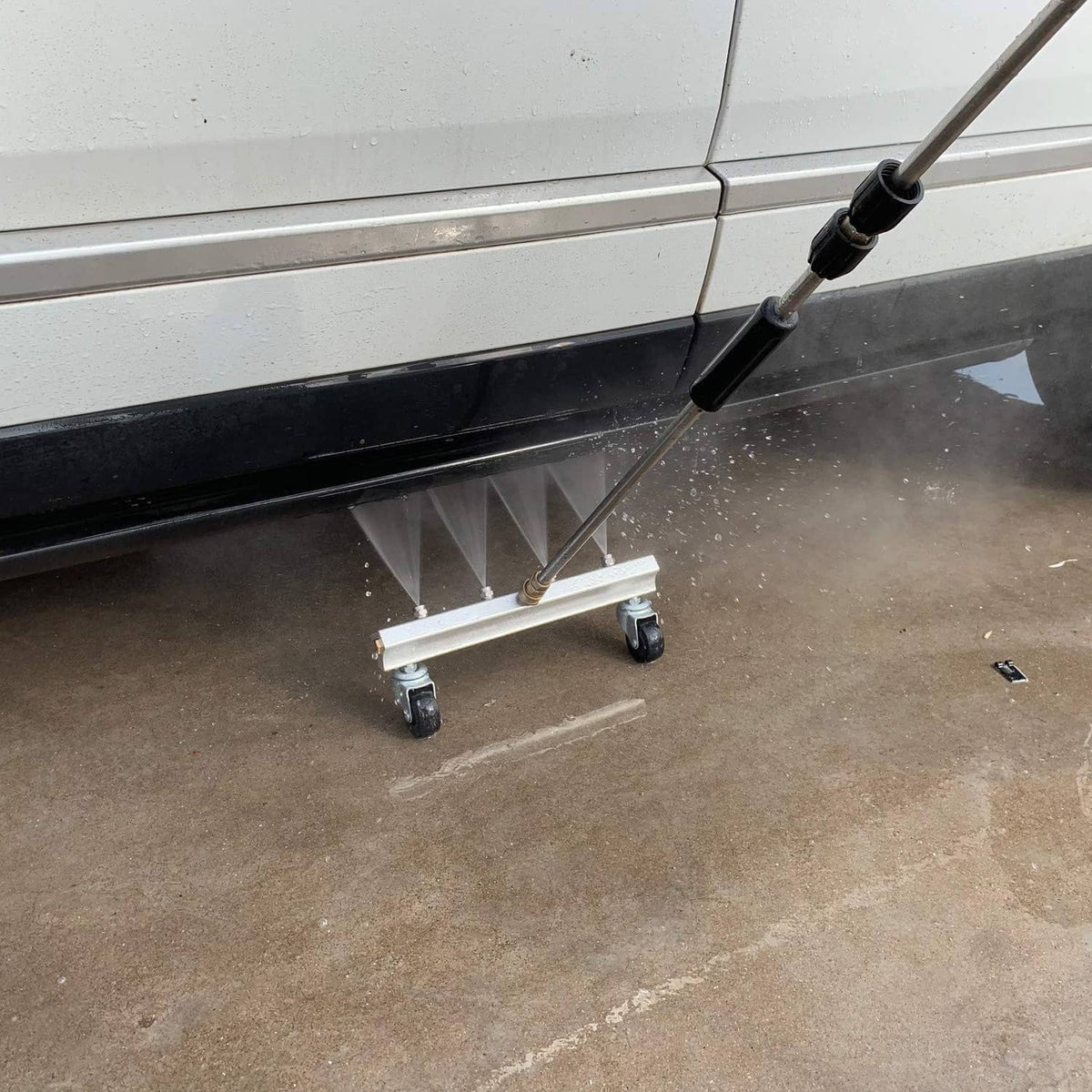 Undercarriage cleaner frame with four caster wheels and wand connected to central inlet