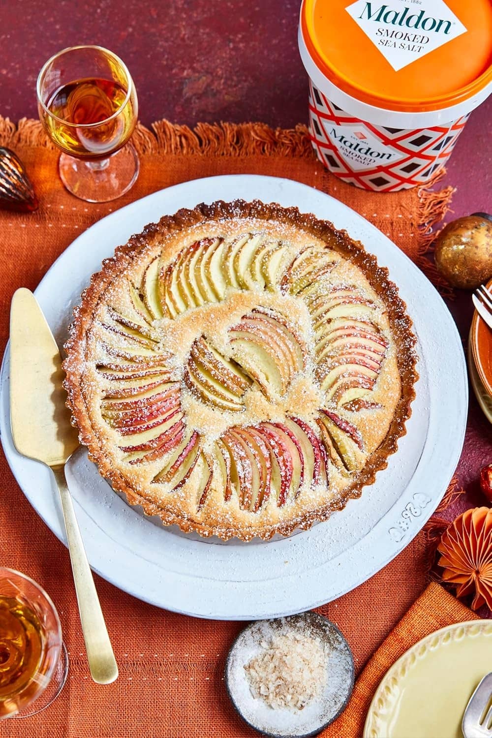 Smoked sea salt flakes bulk tub with orange lid next to topped pie