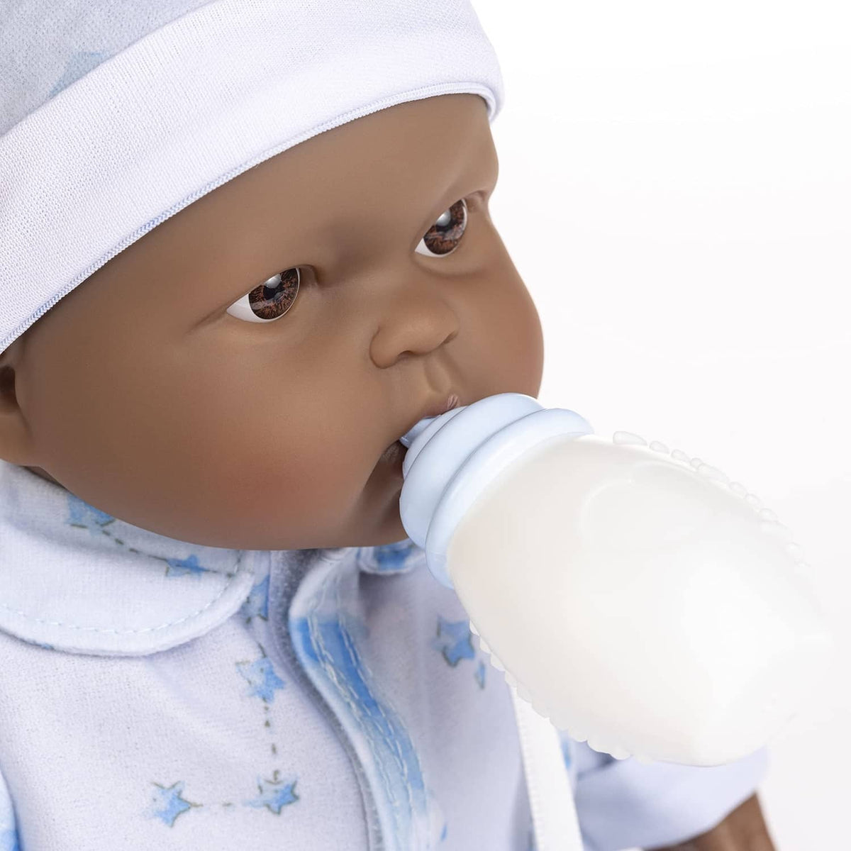 Close-up of a blue-dressed baby doll holding a white bottle near its mouth