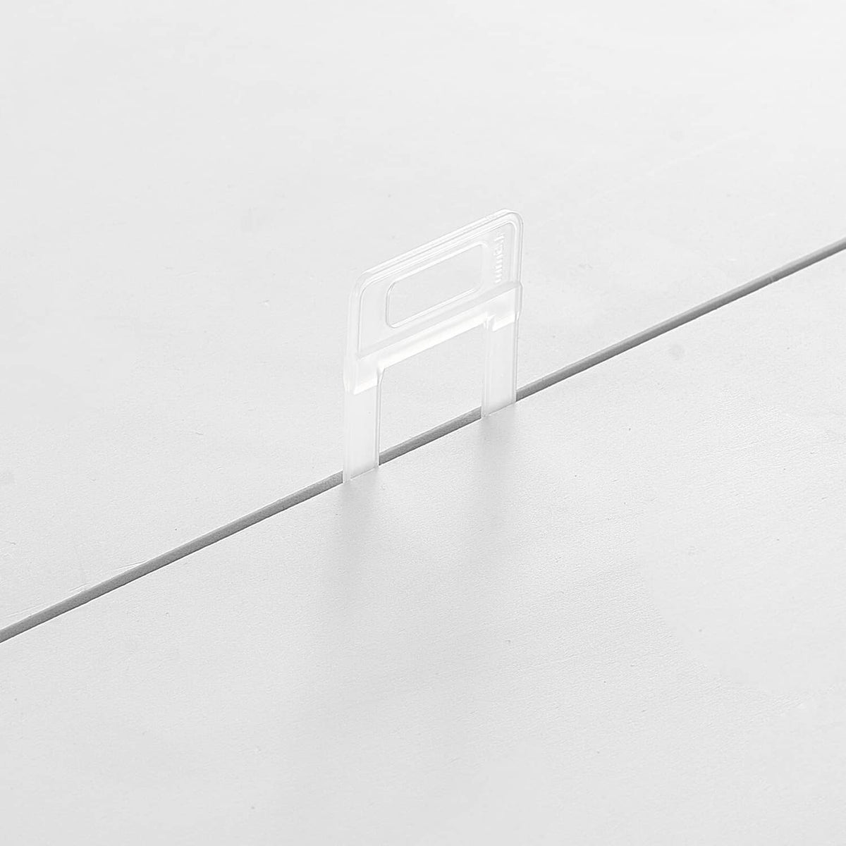 Clear tile leveling spacer clip installed at a tile joint for straight, even alignment