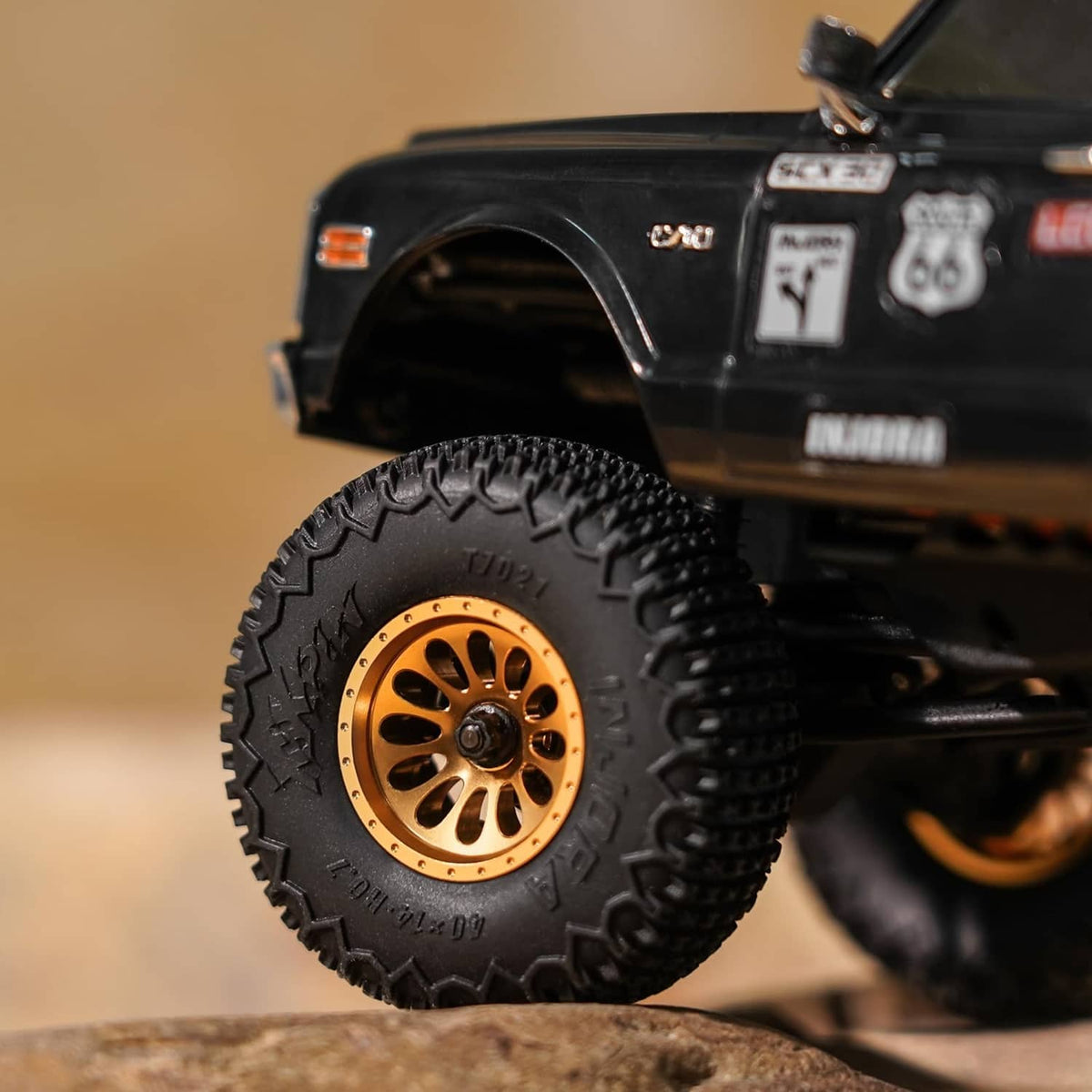 RC wheel with gold beadlock rim and black knobby tire tread on black chassis
