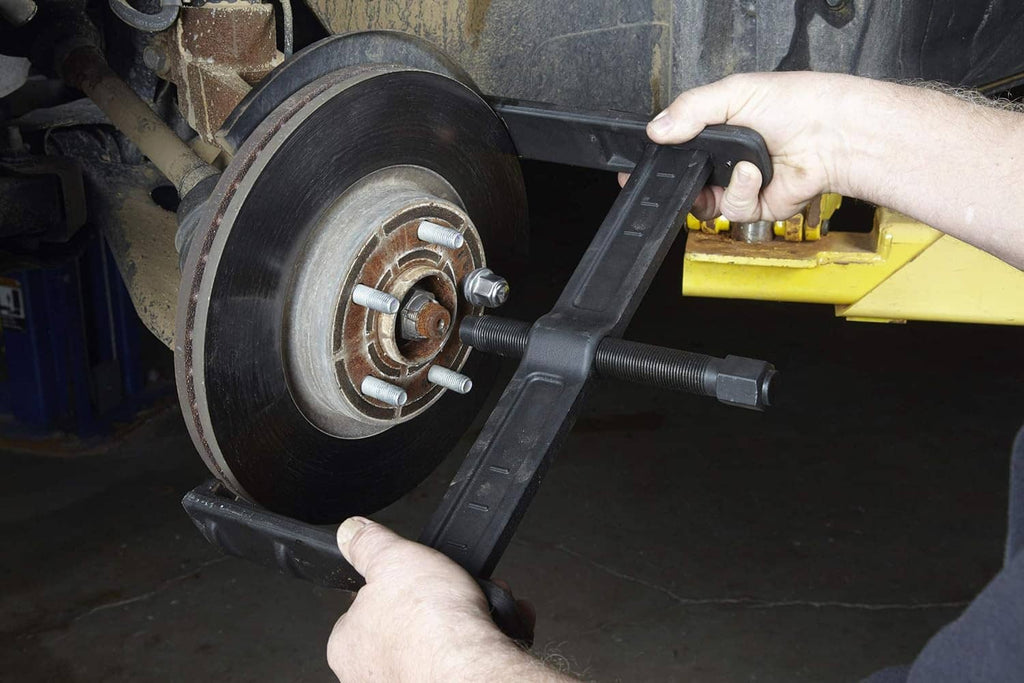 Brake rotor puller placed on wheel hub with threaded puller screw and mounting arms