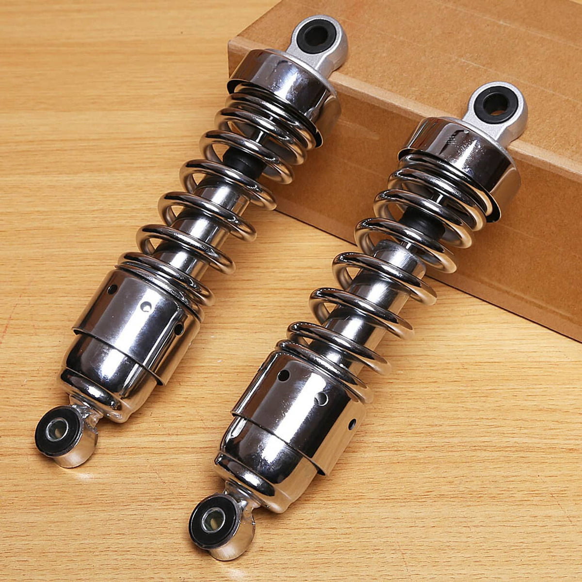 Pair of rear shocks with black coil springs, chrome body, and top mounting eyes