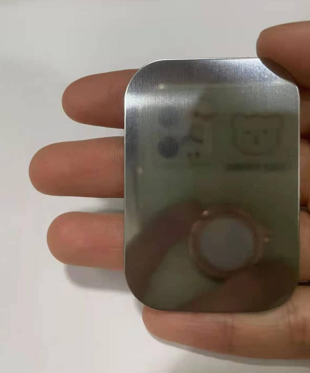 Brushed silver rectangular metal plate held in hand with central circular hole