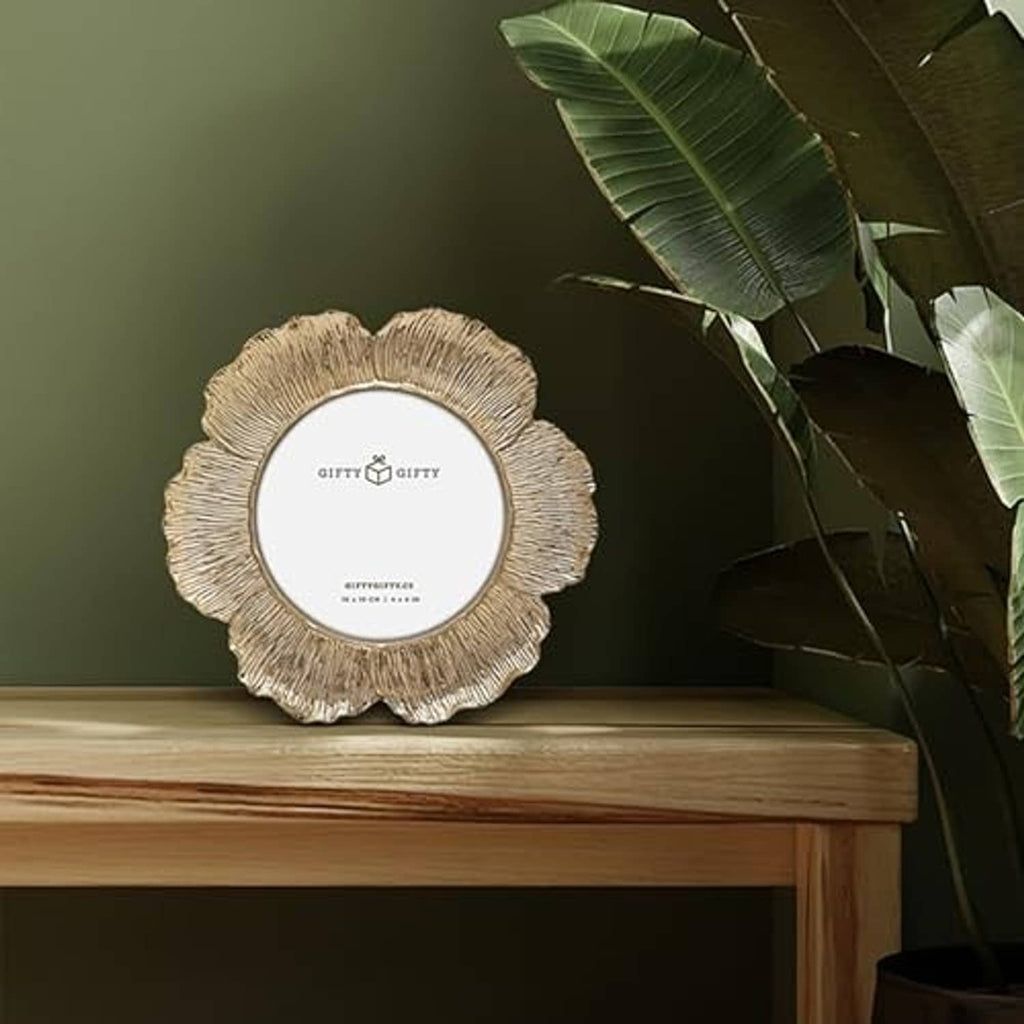 Gold circular floral photo frame standing on a tabletop, textured ridged border.