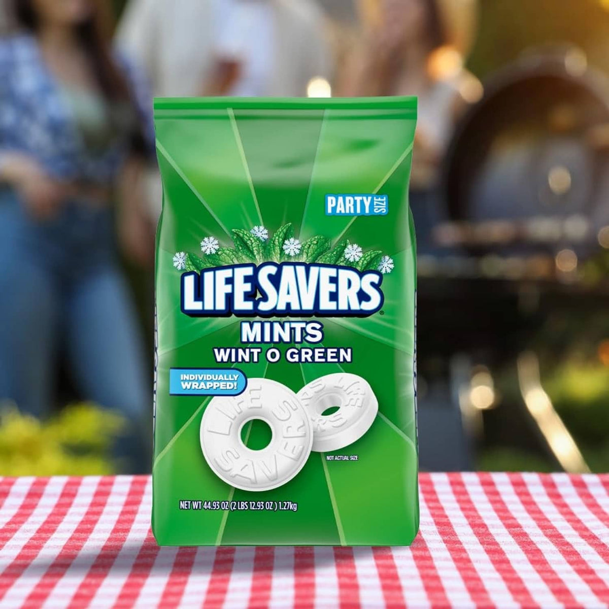 Green LIFE SAVERS mints bag with white mint discs on a striped table