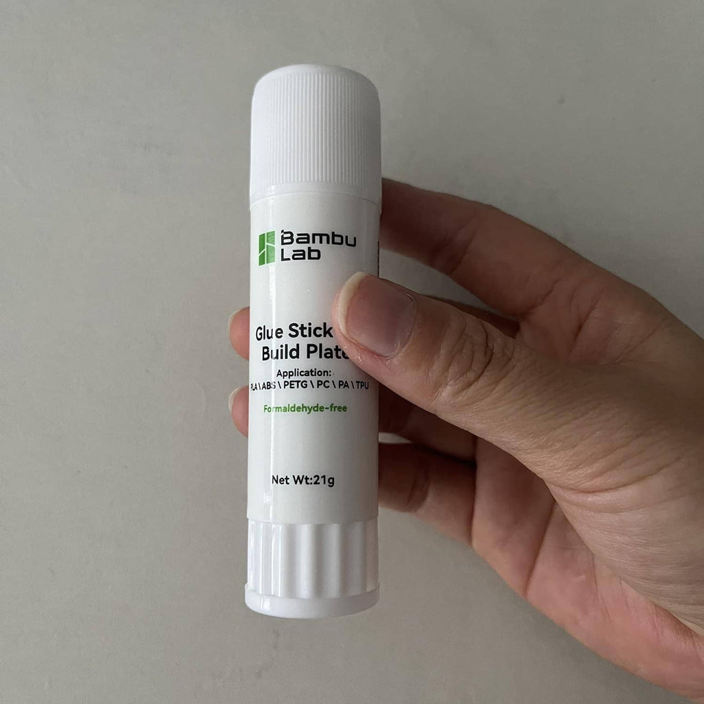 Bambu Lab glue stick for build plate, white bottle held in hand close-up