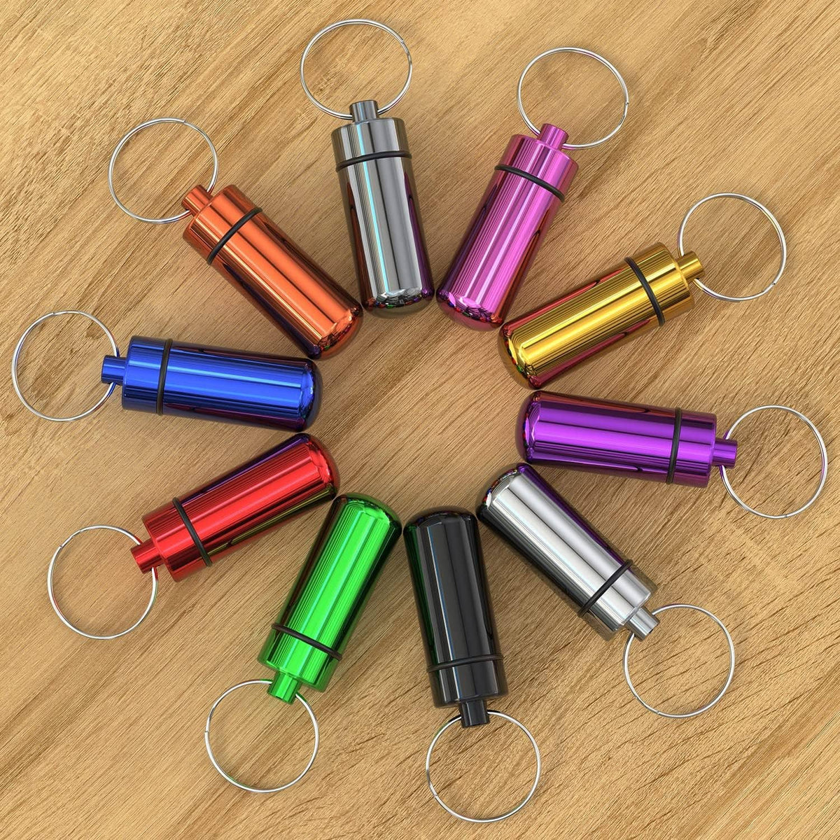 Assorted color pill cases with metal key rings laid out on wood surface.